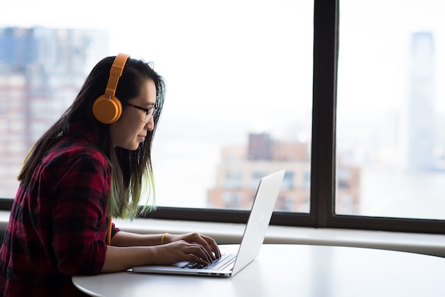 lena sitting at a table on her laptop with headphones on